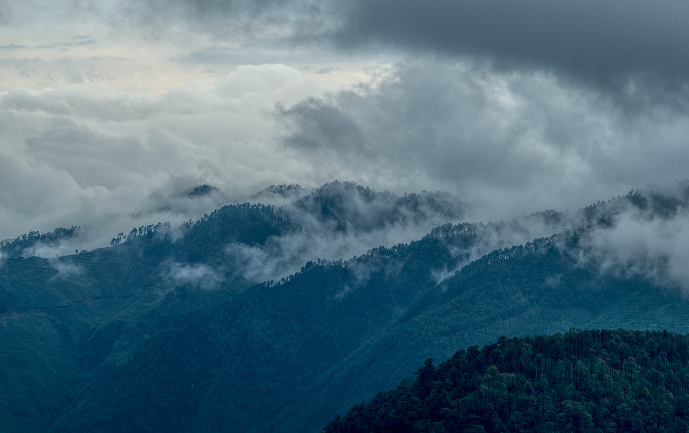 Clouds floating around on a distant hill